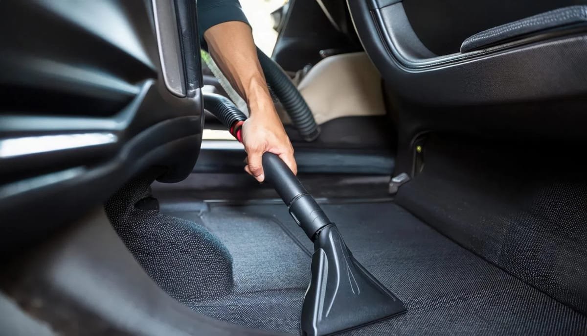 Technician performing deep interior detailing on car carpets