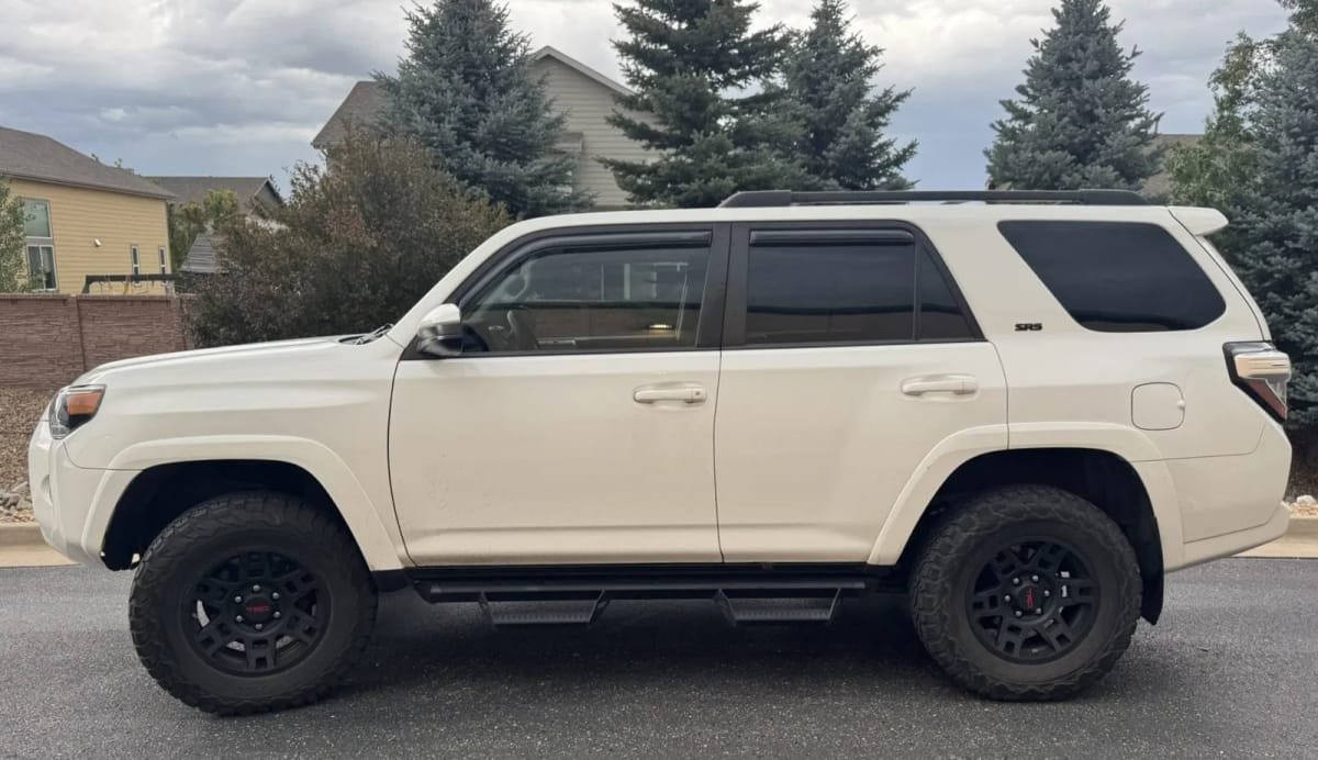 A white Toyota 4Runner SR5 with a professional lift kit, dark window tint, and aftermarket wheels.